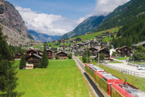 Bergpanorama und ganz viel Grün – der Zug durchquert ein alpines Hochtal.